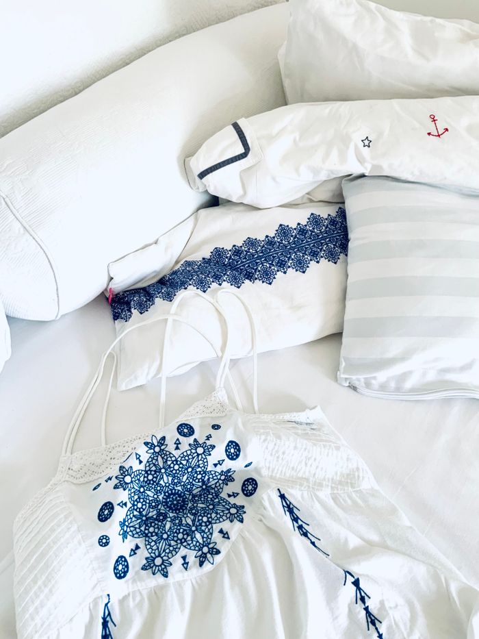 Elegant white bedding ensemble featuring intricate blue embroidery designs.