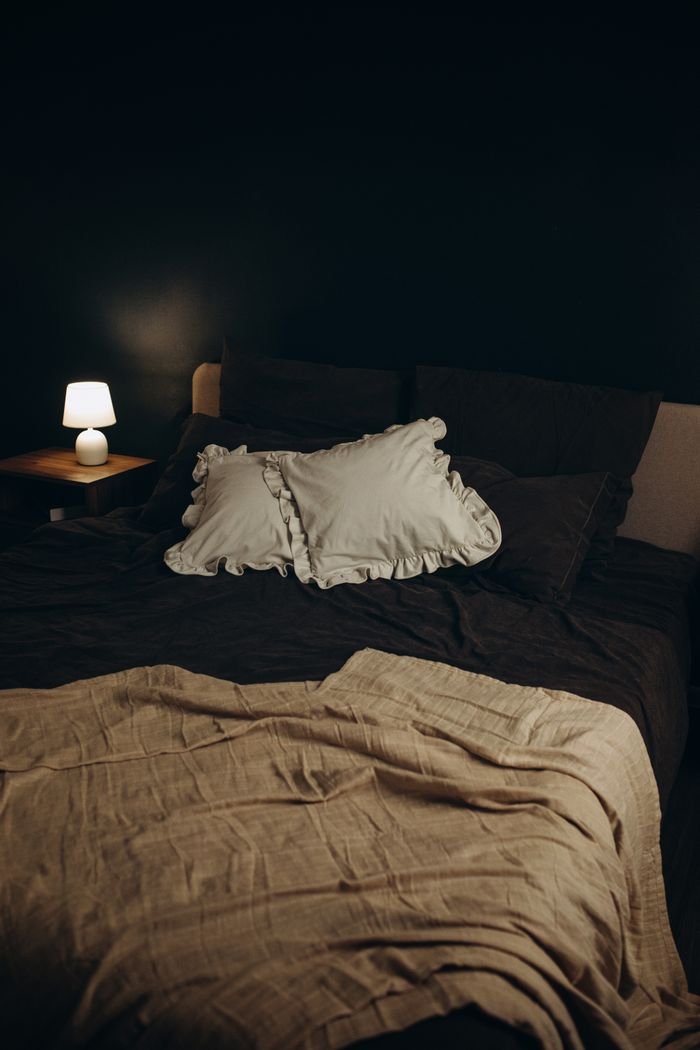 Elegant bedroom setup featuring a soft, cozy bed with a lit bedside lamp creating a warm ambiance.
